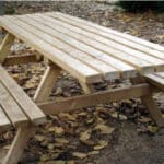 Photo d'une table de pique nique en bois monobloc au près d'un arbre