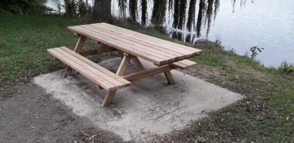 Photo d'une table de pique nique en bois monobloc au près d'un point d'eau