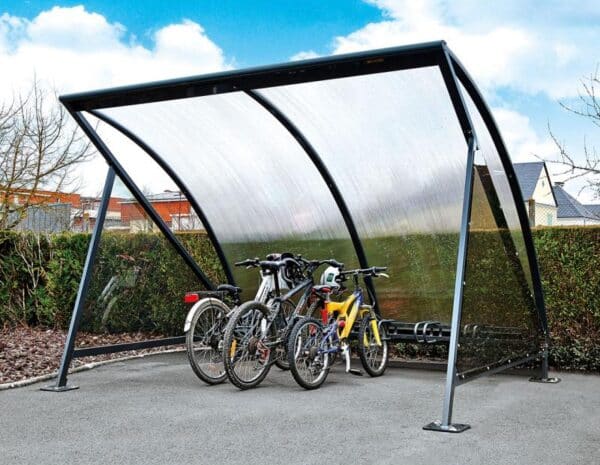 Photo de trois vélos accrochés à un rack sous un abri vélos demi-lune