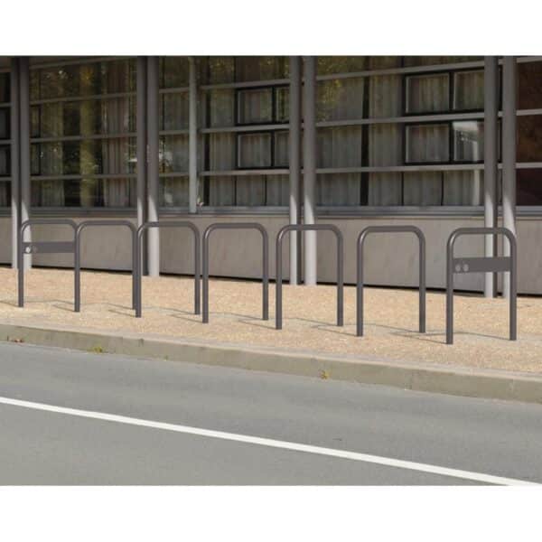 Photo de 7 arceaux vélos simple peint gris sur un trottoir