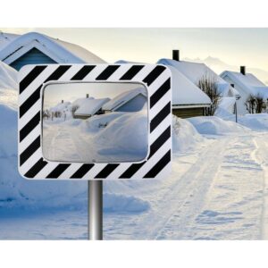 Photo illustrative d'un miroir rectangulaire anti-givre / anti-buée routier pour agglomération à bords noirs et blancs, avec une route et des maisons enneigées en arrière plan