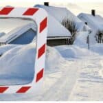 Photo illustrative d'un miroir industriel spécial hivers avec une bordure rouge et blanche rectangulaire, avec une rue et des maisons enneigées en arrière plan