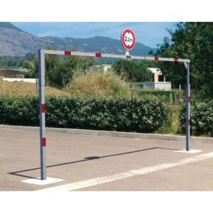 Photo d'un portique économique tournant acier et rouge avec un panneau de limitation de hauteur à 2.2m à l'entrée d'un parking, avec des montagnes en arrière plan