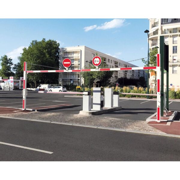 Photo de deux demi portiques universels tournants rouges et blancs à l'entrée et à la sortie d'un parking, surplombés d'un panneau sens interdit pour celui de la sortie et d'un panneau de limitation de hauteur à 2.1m pour celui de l'entrée