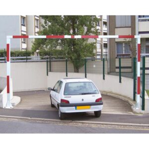 Photo d'une voiture blanche passant en-dessous d'un portique universel fixe rouge et blanc à l'entrée d'un parking sous-terrain