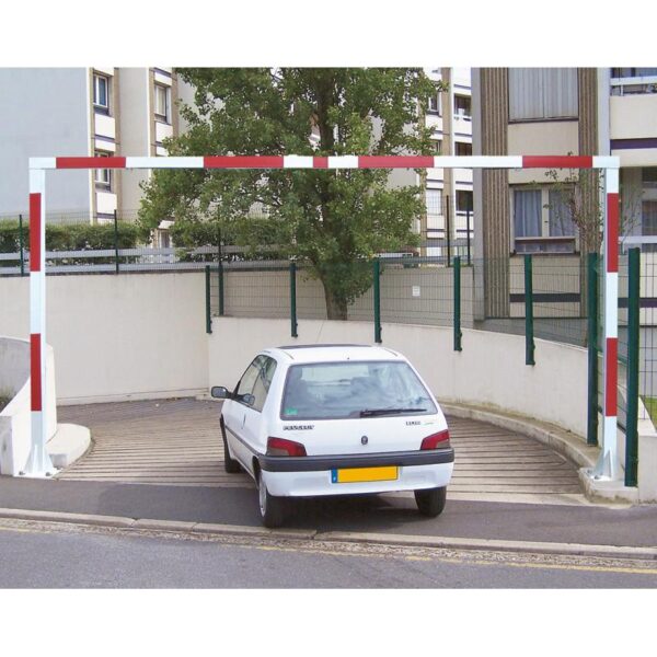 Photo d'une voiture blanche passant en-dessous d'un portique universel fixe rouge et blanc à l'entrée d'un parking sous-terrain