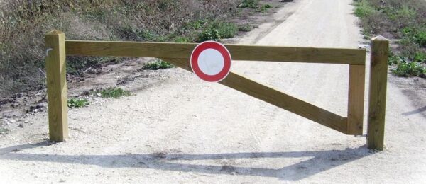 Photo d'une barrière ouvrante en pin traité à l'entrée d'un chemin avec un panneau B0 au milieu