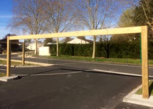 Photo d'un portique fixe en bois grande portée à la sortie d'un parking, au bord d'une route