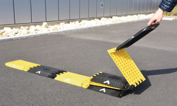 Photo illustrative d'un usager repliant le ralentisseur pliable, transportable et déplaçable jaune et noir
