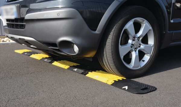 Photo d'une voiture roulant sur un ralentisseur pliable, transportable et déplaçable jaune et noir