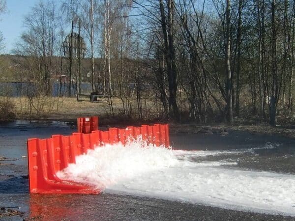 Photo d'illustration d'une barrière anti-inondation rouge en action, arrêtant l'écoulement de l'eau