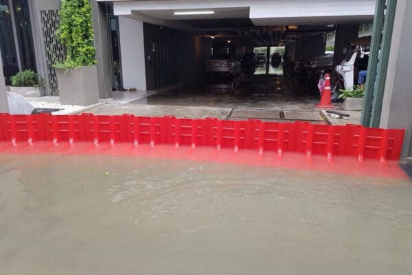 Photo d'illustration d'une barrière anti-inondation rouge en action, protégeant un parking couvert