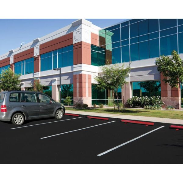 Photo d'illustration d'une butée de parking en acier laqué rouge sur un parking devant un bâtiment vitré