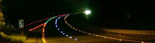 Photo d'une route aménagée avec des plots de route en verre trempé de plusieurs couleurs (rouge, blanc, bleu et vert)