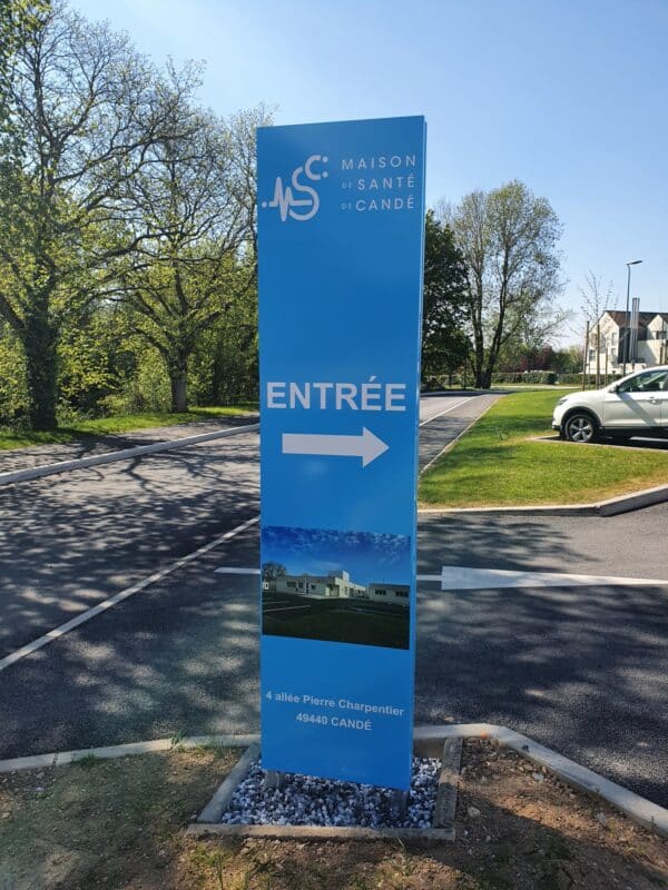 Photo d'un totem d'entreprise bleu clair indiquant une entrée de parking de la maison de santé de Candé