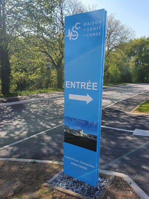 Photo d'un totem d'entreprise bleu clair indiquant une entrée de parking de la maison de santé de Candé