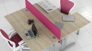 Photo de deux bureaux sisma avec plateau mélaminé bois clair séparés par une toile de fond rose