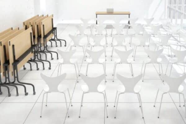 Photo de tables de conférence plateaux rabattables rangées près d'un mur dans une salle de conférence