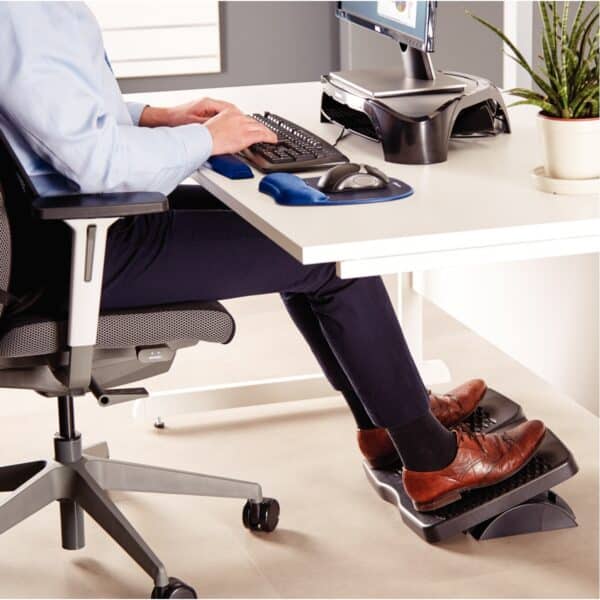 Photo d'un homme posant ses pieds sur un repose-pieds refresh sous un bureau