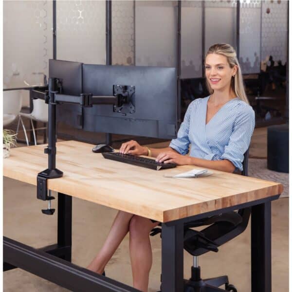 Photo d'une femme assise à un bureau avec un bras support de 2 écrans côte à côte