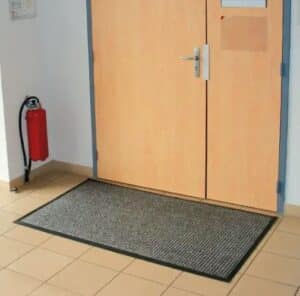 Photo d'un tapis d'entrée professionnel d'intérieur gris au pied d'une porte en bois