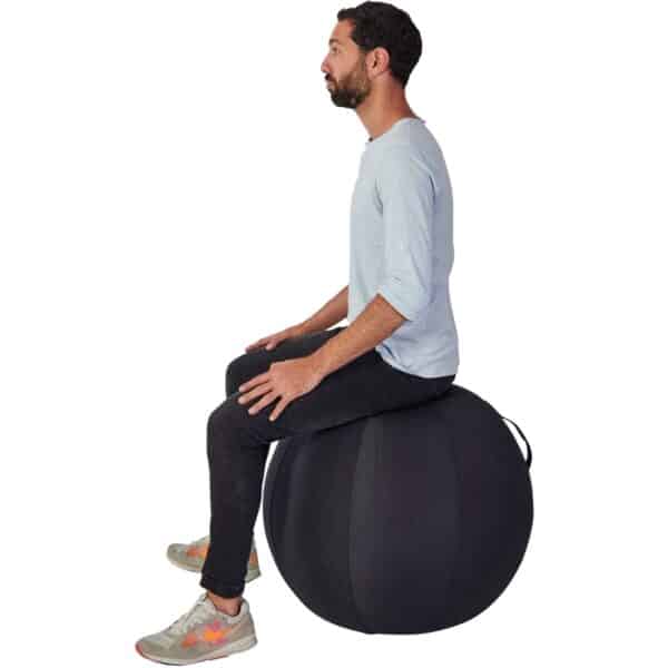 Photo d'un homme assis sur un ballon d'assise ergonomique noir