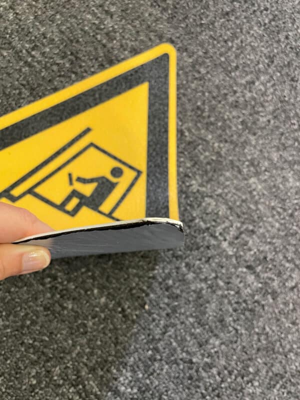 Photo montrant l'épaisseur et le dessous d'un pictogramme préfabriqué résine adhésif triangulaire jaune