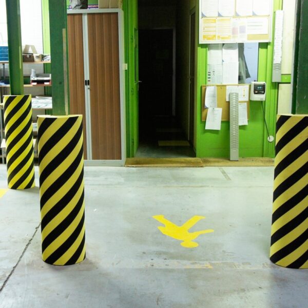 Photo de protections industrielles en mousse à bandes jaunes et noires dans un espace de production