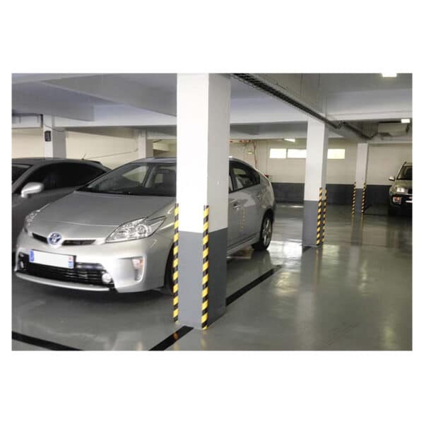 Photo de cornières de protection à bandes jaunes et noires sur le bord de poteaux dans un parking couvert