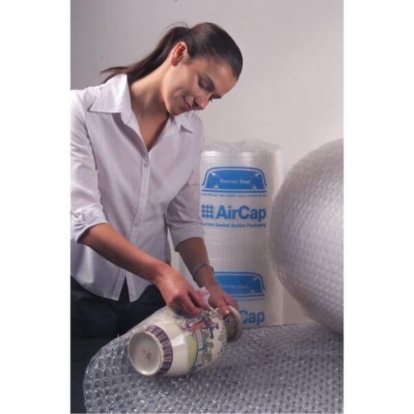 Photo d'une femme utilisant un rouleau de film à bulles pour protéger un vase