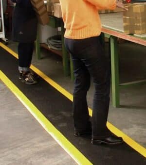 Photo de personnes travaillant debout sur un tapis antifatigue noir et jaune