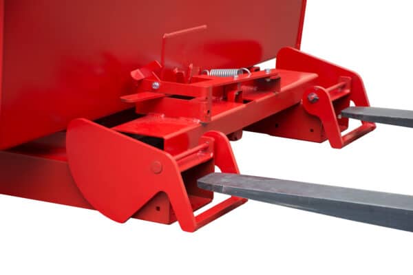 Photo gros plan de la fixation d'une benne basculante automatique rouge sur les lames d'un chariot élévateur